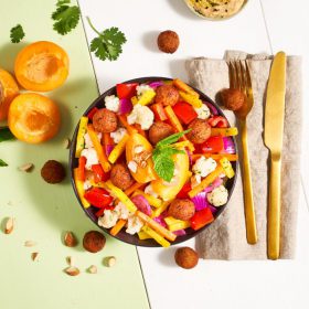 Ein bunter Salat mit FRoSTA Tiefkühlprodukten: gelbe Bohnen, rote Paprika, Blumenkohl, Zwiebeln, Falafelbällchen & Aprikosen, garniert mit Minze.