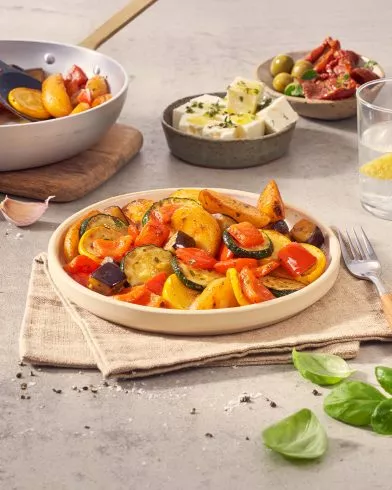 Ein Teller mit gerösteten FRoSTA Tiefkühlprodukten Gemüsepfanne alla mediterranea mit Zucchini, Kartoffeln, Aubergine und Paprika auf einer Serviette.