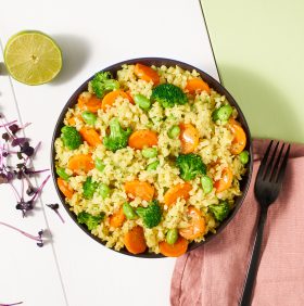 Eine Schüssel gelber Reis mit Brokkoli, Karotten und Edamame von FRoSTA-Tiefkühlprodukten bringt bunte Vielfalt auf den Tisch.