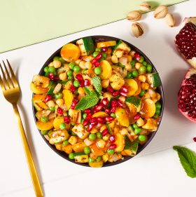 Eine Schüssel bunter Salat mit Kichererbsen, Erbsen, FRoSTA Tiefkühlprodukten, gelben Tomaten, Zucchini, Granatapfelkernen & Minze – purer Genuss!.