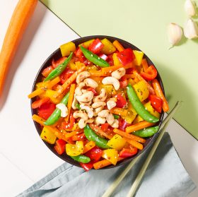 Eine Bowl mit FRoSTA Tiefkühlgemüse, Paprika, Karotten, Zuckerschoten, Cashews und Sesam. Asiatische Inspiration aus aller Welt.