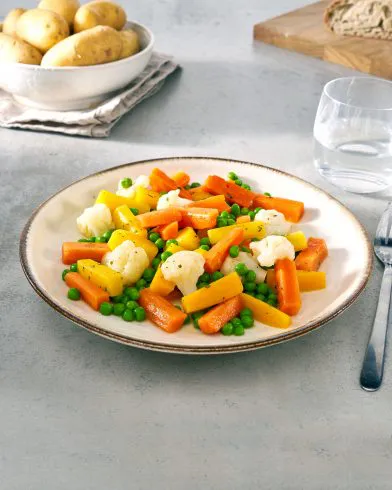 Ein Teller mit FRoSTA-Tiefkühl-Gemüsepfanne aus Karotten, Erbsen, Blumenkohl und gelben Karotten bringt Nordische Küche nach Hause.