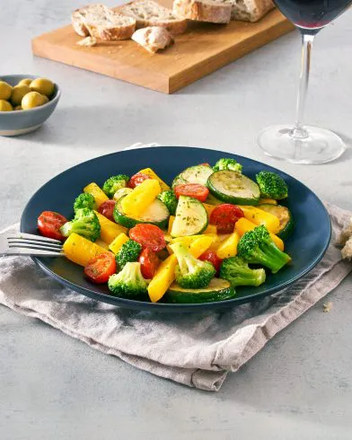 Ein Teller FRoSTA Gemüsepfanne mit gelbem Paprika, Kirschtomaten, Brokkoli und Zucchini – inspiriert von toskanischer Küche.