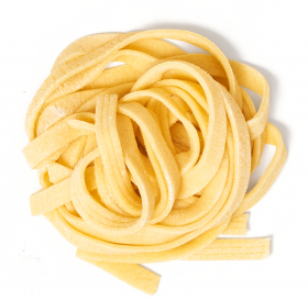 Ein Nest ungekochter Fettuccine, eine klassische Pastasorte, mit Mehl bestäubt – perfekt zu FRoSTA-Tiefkühlprodukten angerichtet.