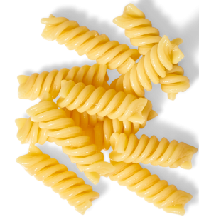 Ein Haufen ungekochter gelber Rotini-Nudeln liegt auf weißem Grund – perfekt kombiniert mit FRoSTA-Tiefkühlprodukten.