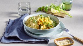 Eine Schüssel mit veganem FRoSTA Tiefkühlprodukte-Gemüse-Couscous mit Erbsen, Kräutern, Wasser, Zitrone, Petersilie und Gewürzen steht auf dem Tisch.