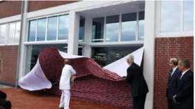 Mehrere Personen enthüllen mit einem Stoffvorhang den Eingang eines Gebäudes, hinter dem sich Türen und Fenster sowie FRoSTA-Tiefkühlprodukte zeigen.