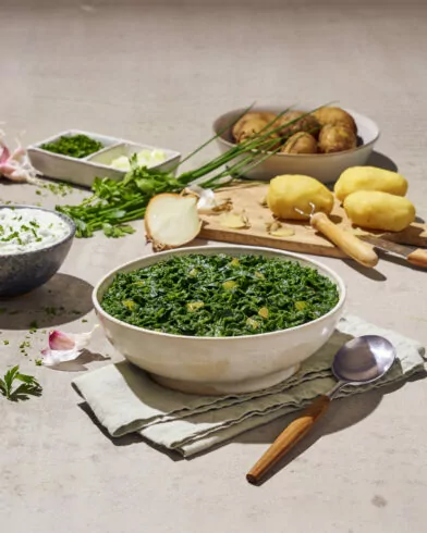 Eine Schüssel mit gekochtem Gemüse, darunter zarte FRoSTA-Tiefkühlprinzessbohnen, steht auf einer Serviette mit Löffel.