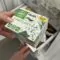 Eine Hand hält eine Packung FRoSTA Kräuter Schnittlauch über einer geöffneten Gefrierschublade mit FRoSTA Tiefkühlprodukten.