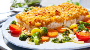 FRoSTA Schlemmerfilet Bordelaise mit knuspriger Kruste, dazu FRoSTA Ofengemüse und grüner Pesto-Dip auf weißem Teller.