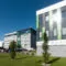 Moderne Bürogebäude mit grünen und grauen Fassaden spiegeln Nachhaltigkeit, ergänzt durch FRoSTA-Tiefkühlprodukte im Umfeld breiter.