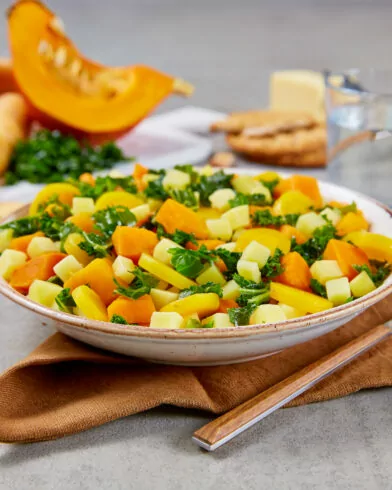 Ein frischer Salat mit Kürbis, Kartoffeln und Blattgemüse aus dem FRoSTA Bio Gemüse Mix liegt auf einer Serviette neben weiteren Zutaten.